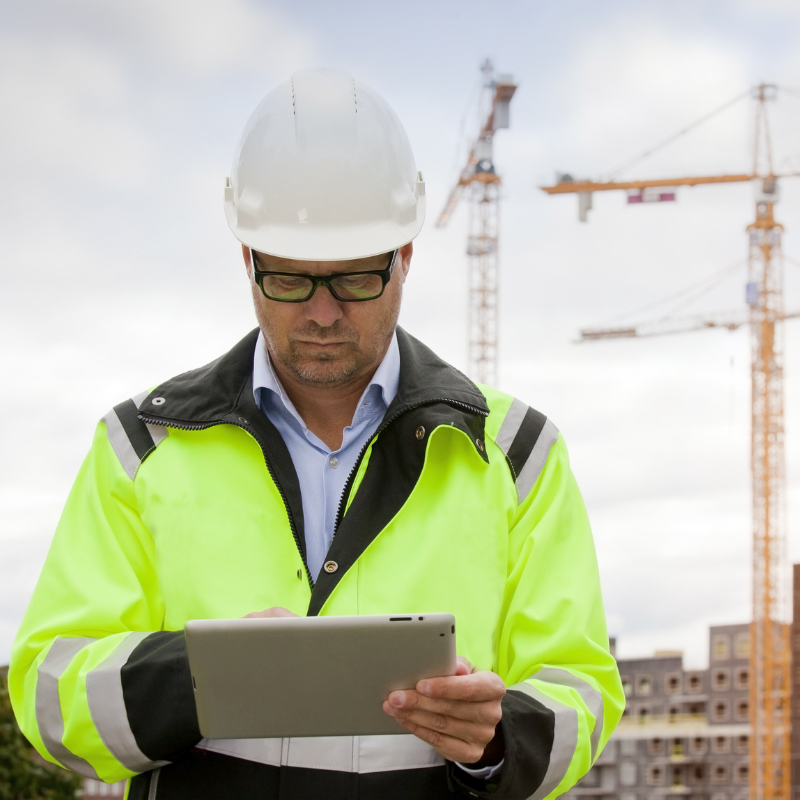 Entreprenør på en byggeplads med en tablet i hånden
