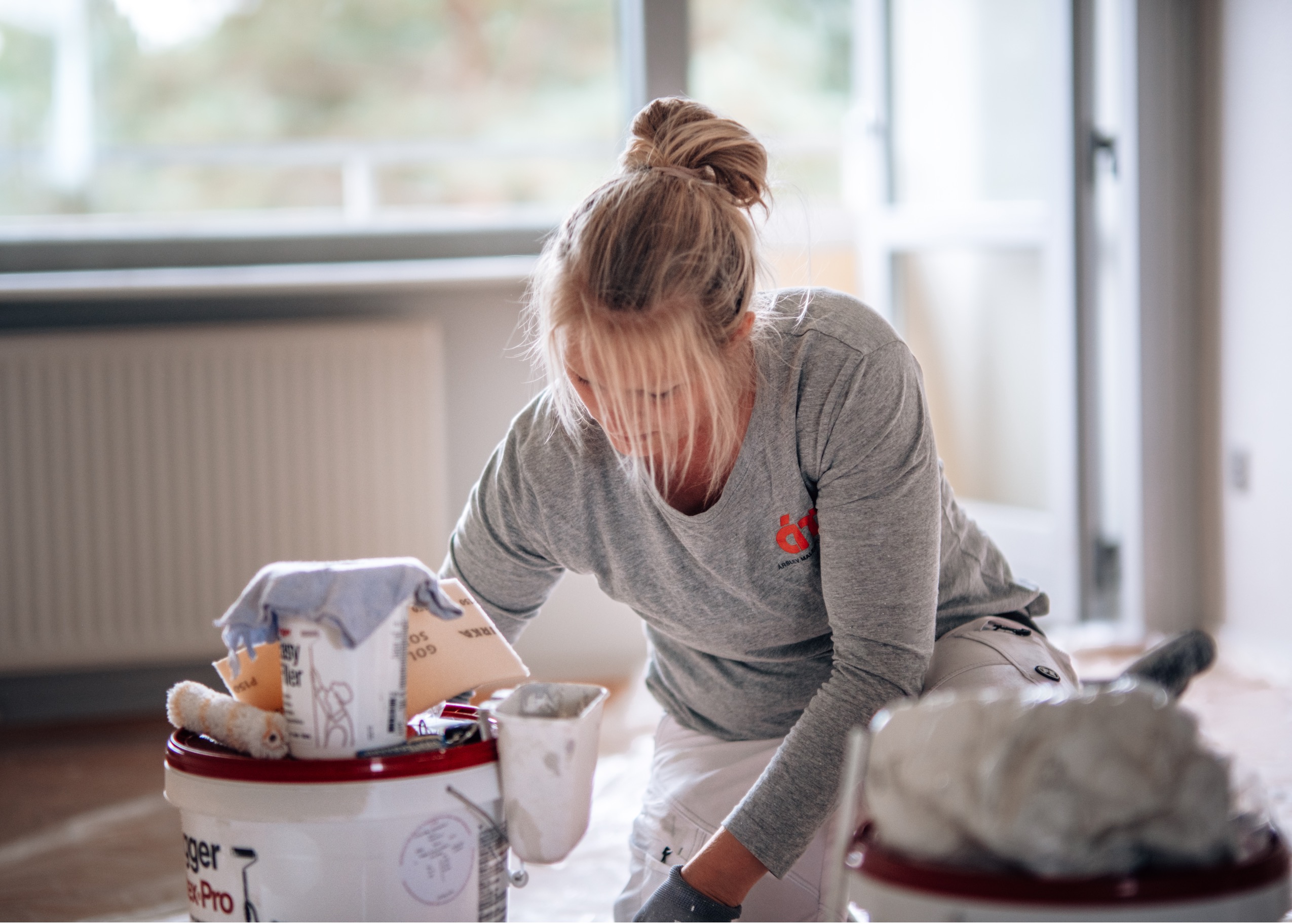 Pige der maler. Håret er sat op. Grå t-shirt